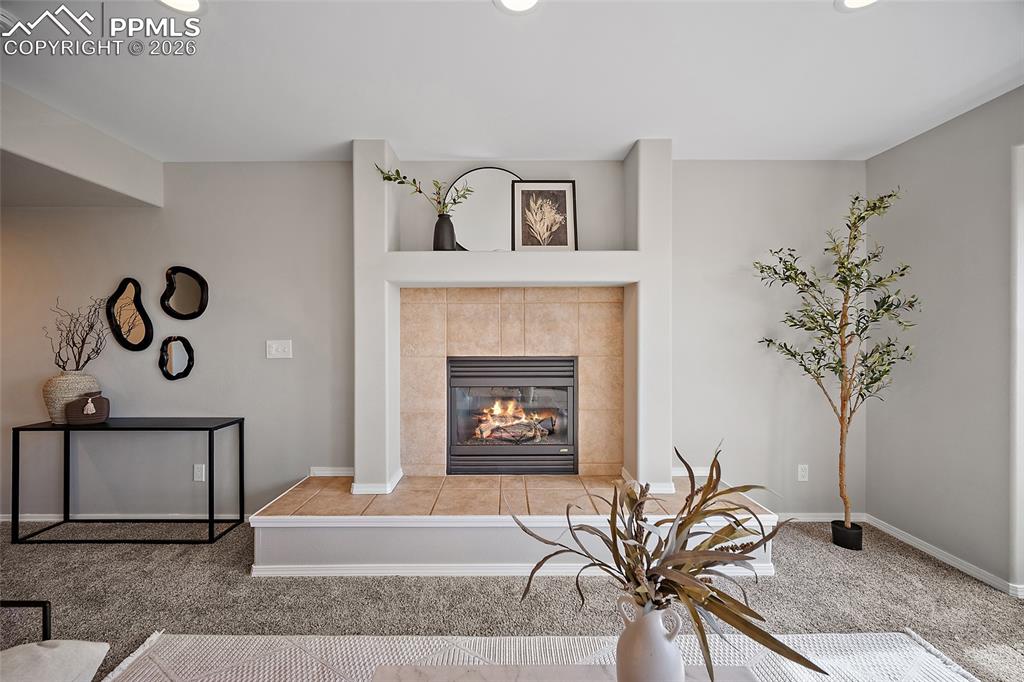 Image 11 of 46: Living area featuring light colored carpet, a fireplace, and recessed light