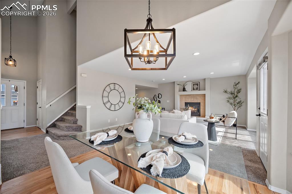 Image 12 of 46: Dining area with light wood-style floors, hanging lights, a tile fireplace,