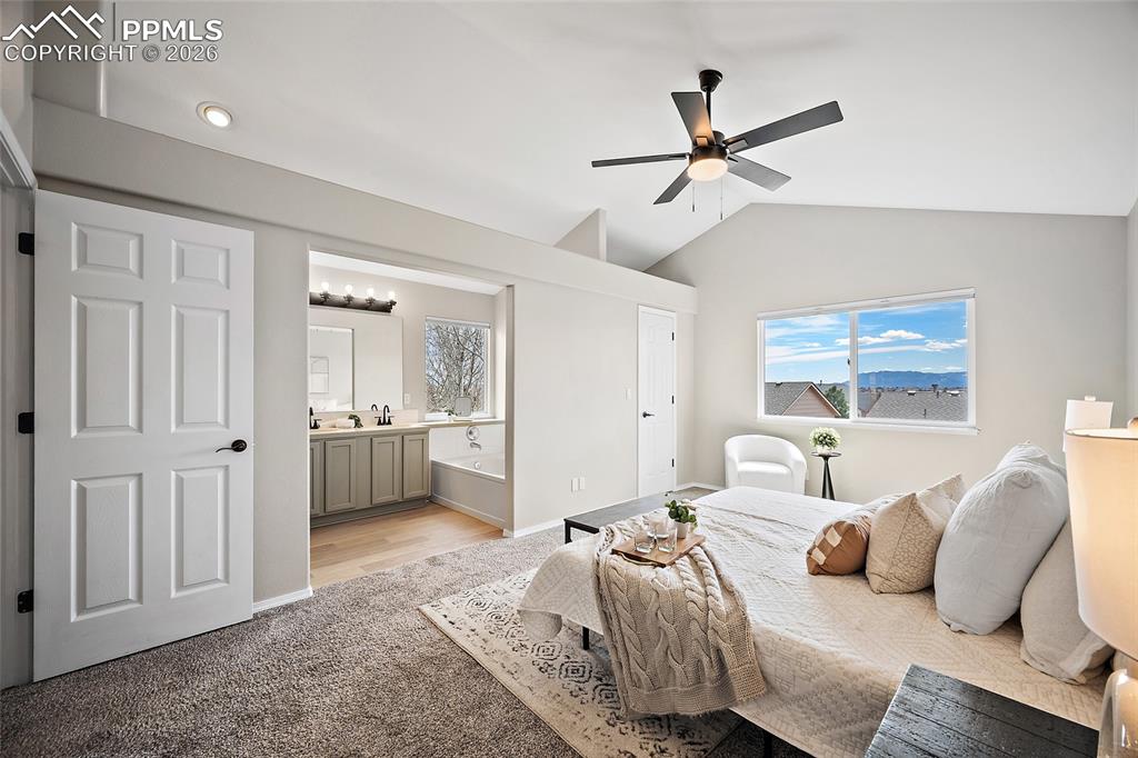 Image 16 of 46: Bedroom with light carpet, vaulted ceiling, ceiling fan, and ensuite bathro
