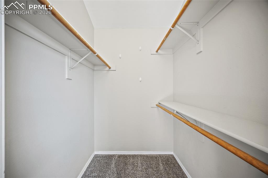 Image 19 of 46: Walk in closet featuring dark colored carpet