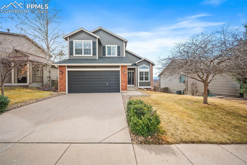 Image 2 of 46: View of front of house with a front lawn, driveway, brick siding, a garage,