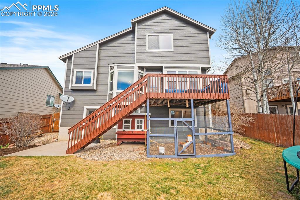 Image 28 of 46: Back of house with a fenced backyard and a wooden deck