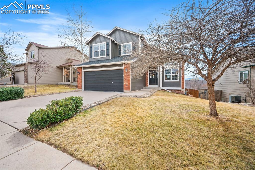 Image 3 of 46: Traditional home featuring brick siding, driveway, and an attached garage