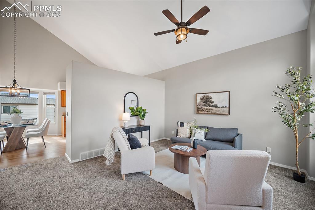 Image 7 of 46: Carpeted living room featuring vaulted ceiling and a ceiling fan