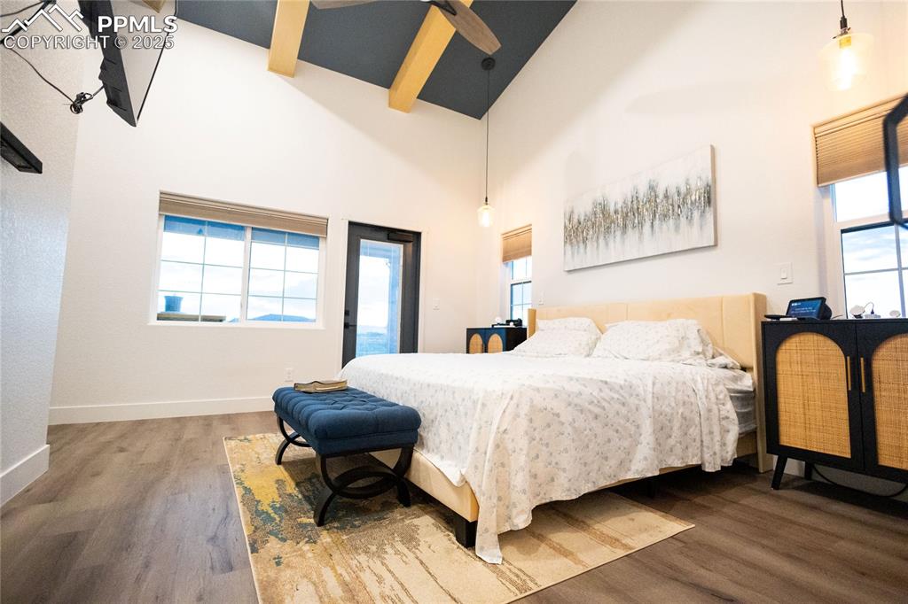 Image 10 of 44: Bedroom featuring high vaulted ceiling, wood finished floors, access to out