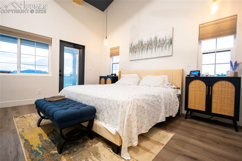 Image 11 of 44: Bedroom with dark wood-style flooring, access to exterior, and a high ceili