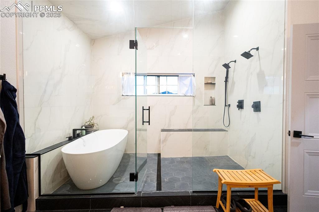 Image 12 of 44: Bathroom with a marble finish shower, a freestanding bath, and tile walls