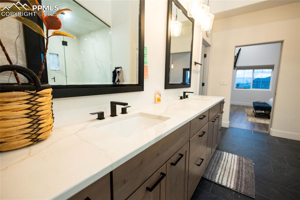 Image 15 of 44: Bathroom featuring double vanity and a marble finish shower