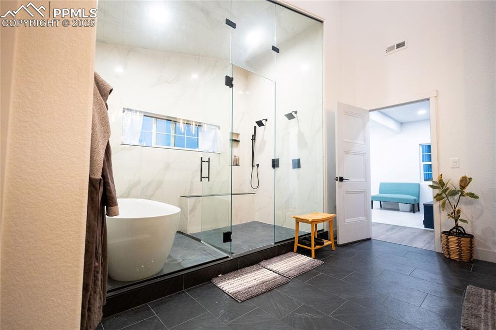 Image 16 of 44: Bathroom with connected bathroom, a marble finish shower, and a freestandin