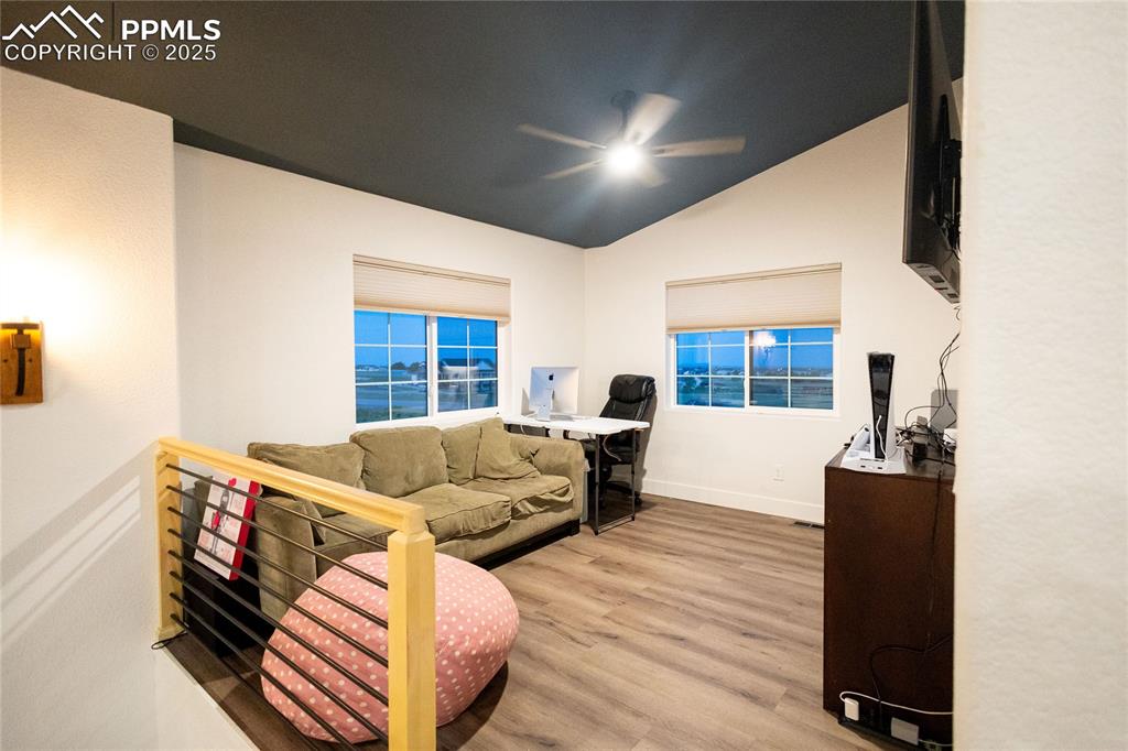 Image 32 of 44: Living area with light wood finished floors, lofted ceiling, and ceiling fa