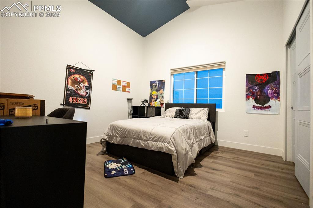 Image 34 of 44: Bedroom 4 with wood finished floors, an office area, a closet, and high vau