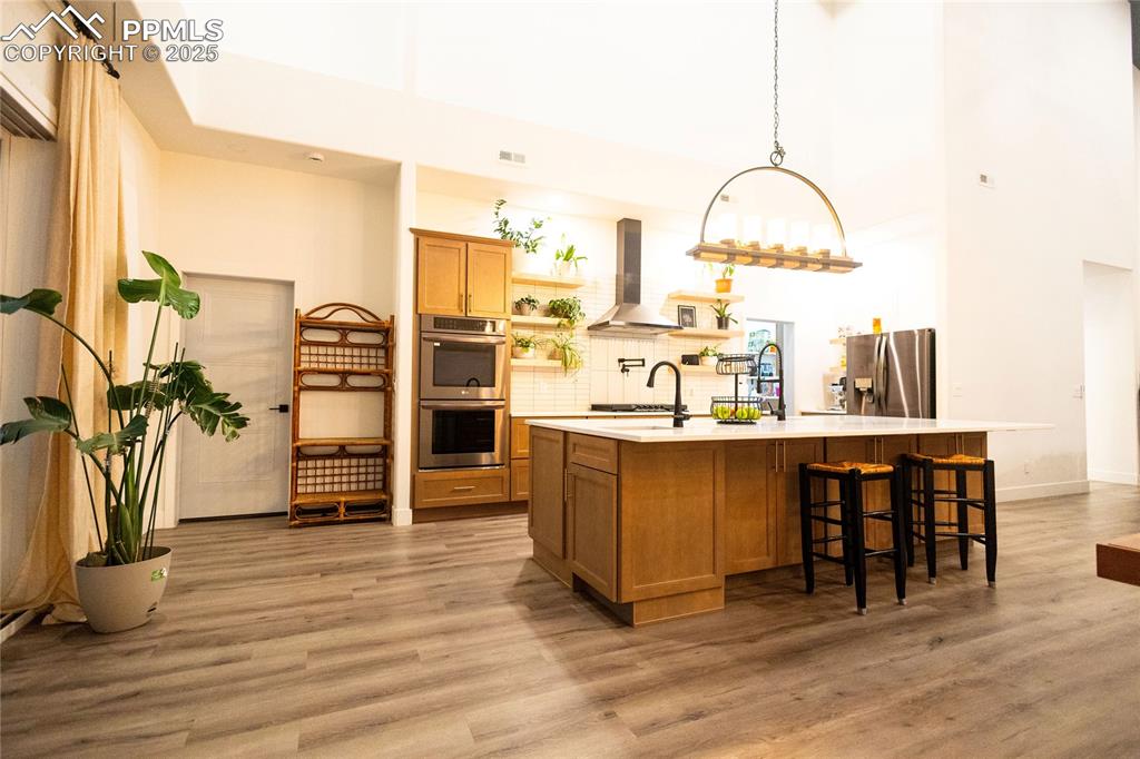 Image 4 of 44: Kitchen featuring open shelves, a kitchen bar, backsplash, brown cabinets,