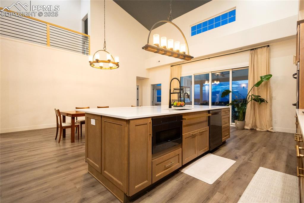 Image 5 of 44: Kitchen with brown cabinets, dark wood finished floors, a towering ceiling,