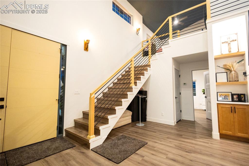 Image 8 of 44: Stairs with wood finished floors and a high ceiling