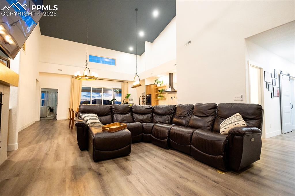 Image 9 of 44: Living area with light wood-type flooring, a chandelier, and a towering cei