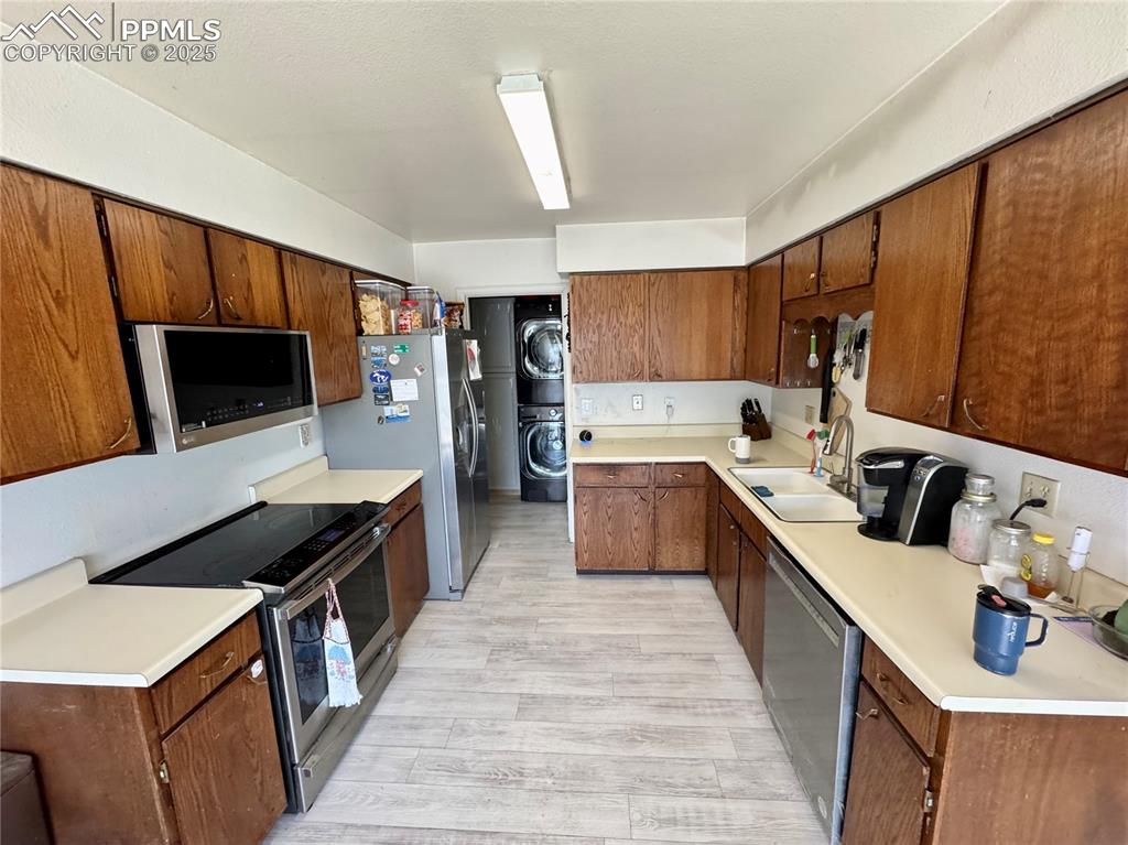 Image 10 of 22: Kitchen featuring estacked washer and dryer, stainless steel appliances, li