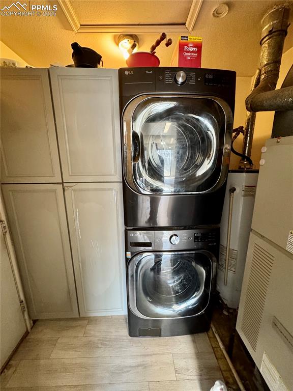 Image 14 of 22: Laundry area featuring cabinet space, water heater, stacked washer and clot