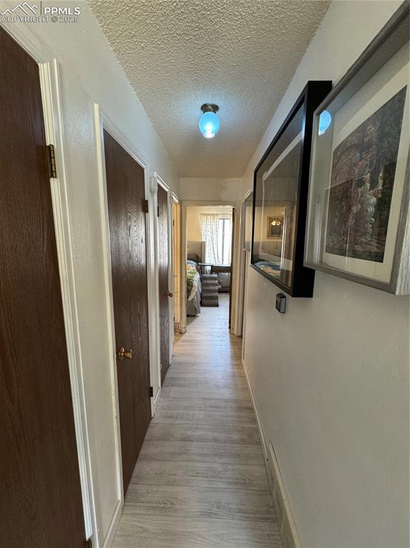 Image 15 of 22: Hallway with a textured ceiling and light wood-style flooring