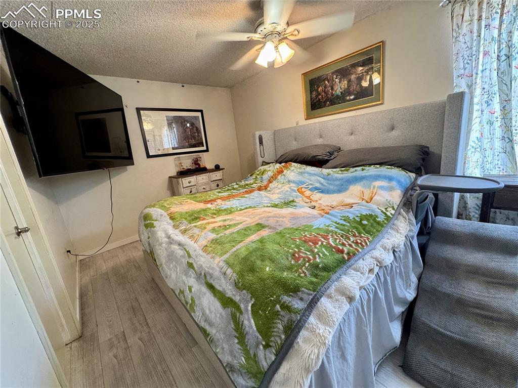 Image 17 of 22: Bedroom featuring a textured ceiling, wood finished floors, and ceiling fan