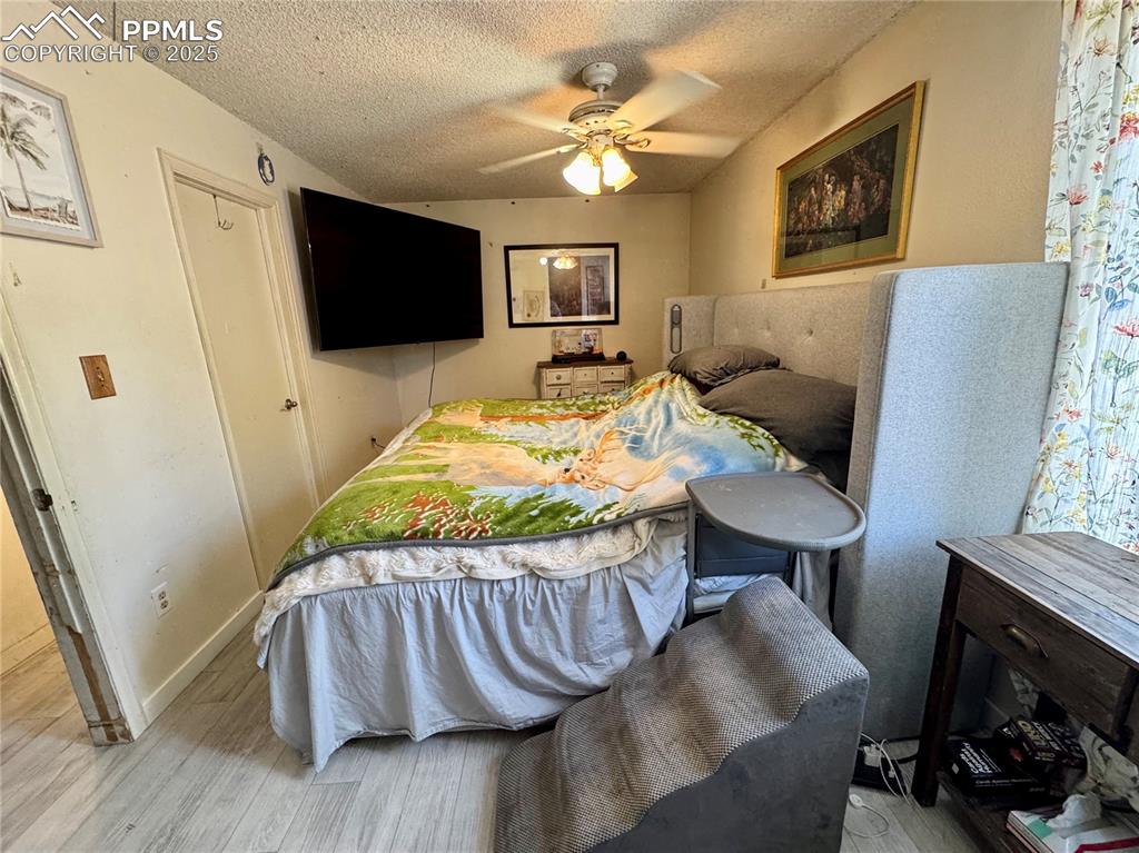 Image 19 of 22: Bedroom with a textured ceiling, wood finished floors, and a ceiling fan