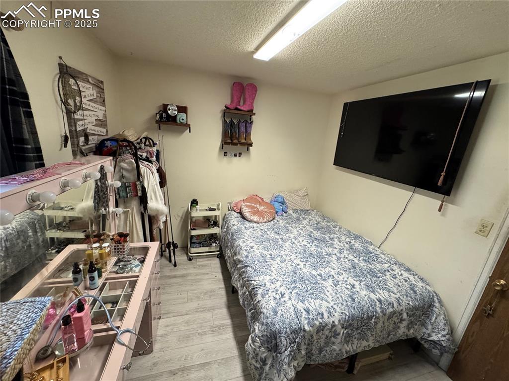 Image 21 of 22: Bedroom with a textured ceiling and light wood-style flooring