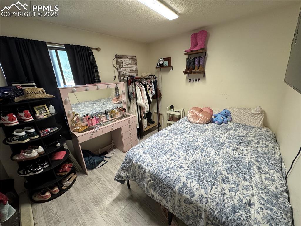 Image 6 of 22: Bedroom with a textured ceiling and light wood-style floors