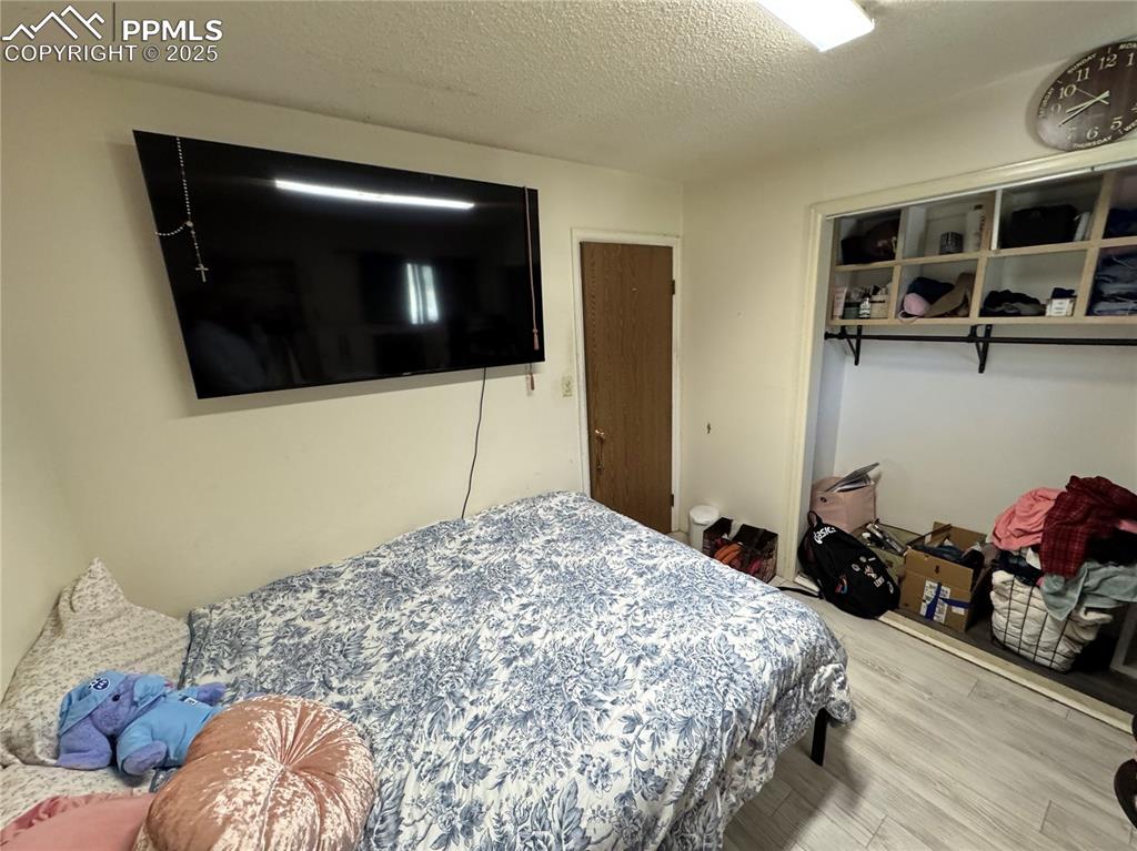 Image 7 of 22: Bedroom with a textured ceiling, wood finished floors, and a closet