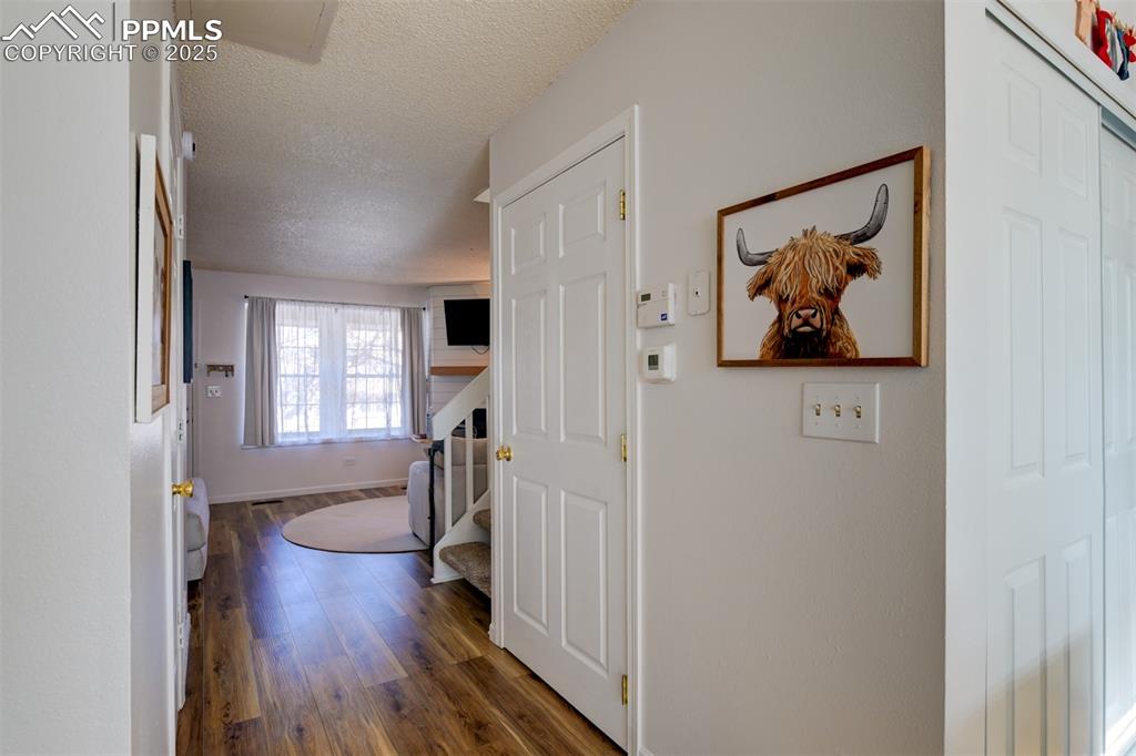 Image 10 of 25: Corridor featuring a textured ceiling, wood finished floors, and stairway t
