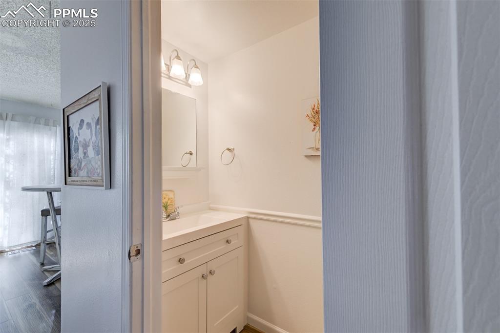 Image 11 of 25: Half Bathroom on the main level with vanity, and wood-style flooring