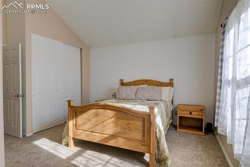 Image 14 of 25: Main Bedroom on the upper level with adjacent bath, vaulted ceiling, carpet
