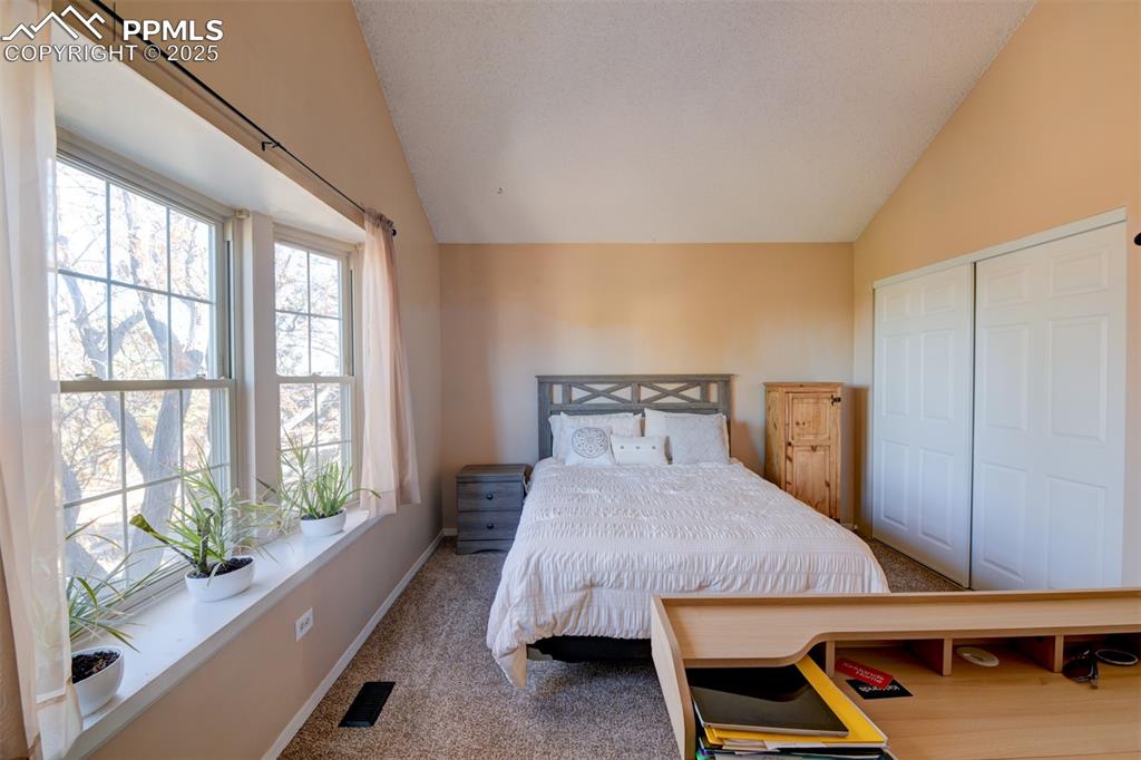 Image 19 of 25: Another view of the 2nd Bedroom with vaulted ceiling, carpet flooring, a cl