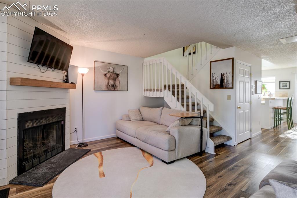 Image 3 of 25: Living room on the main level featuring a wood fireplace, wood finished flo