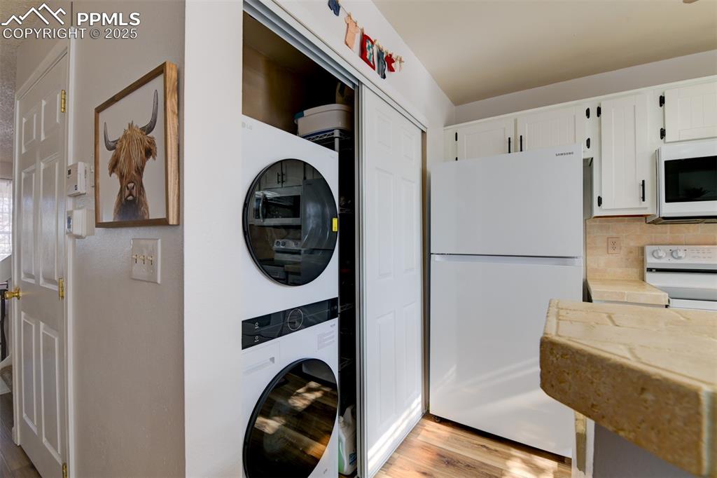 Image 9 of 25: Laundry area on the main level with light wood-style floors and stacked was