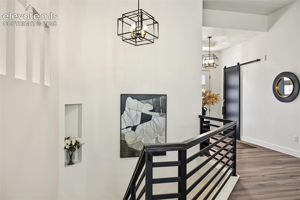 Image 33 of 50: Bright, open hallway featuring elegant chandelier lighting, modern black ir