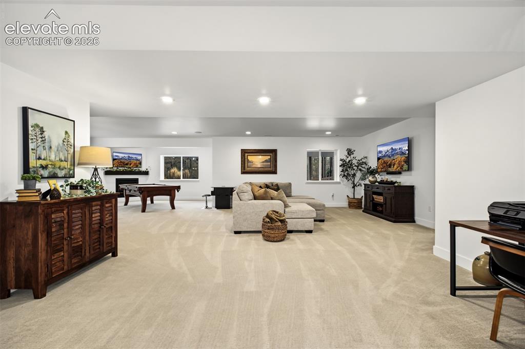 Image 34 of 50: Expansive carpeted area with recessed lighting, multiple windows, and a bui
