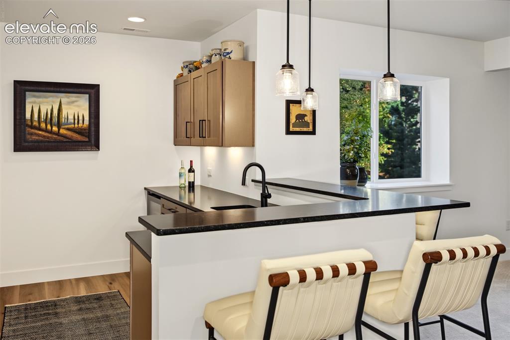 Image 37 of 50: Integrated wet bar featuring dark countertops and a built-in sink