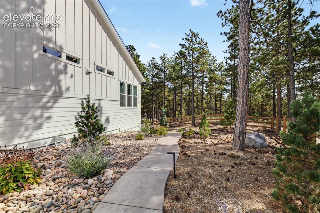 Image 43 of 50: Board and batten siding, multiple window configurations, a paved walkway, a