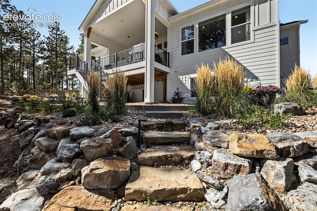 Image 44 of 50: Multi-level exterior with a stone retaining wall, natural stone steps, and 