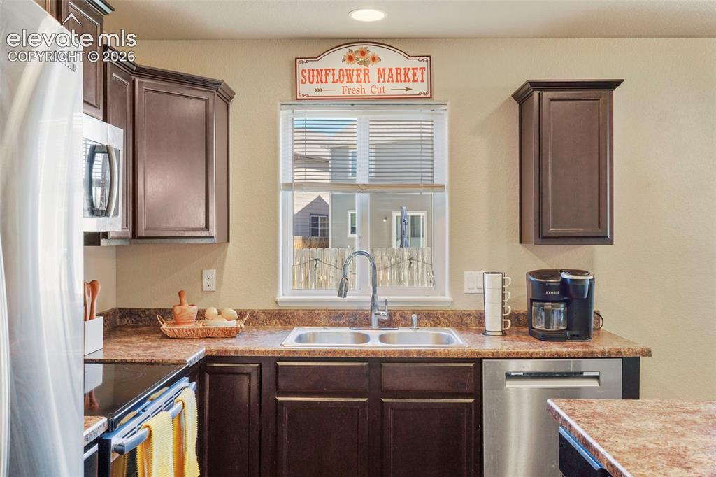 Image 11 of 32: Dark wood-finish cabinetry, stainless steel dishwasher, stainless steel sin