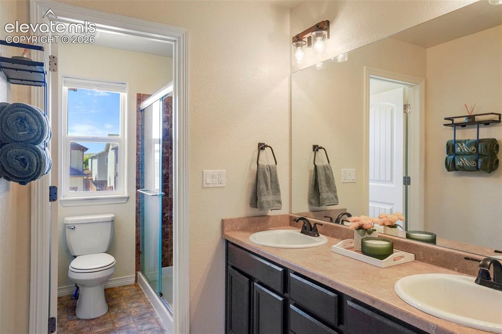 Image 15 of 32: Dual vanity with undermount sinks, bronze finish faucets, and a large wall-
