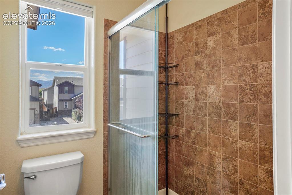 Image 16 of 32: Tiled shower enclosure with a glass door, complete with an integrated showe