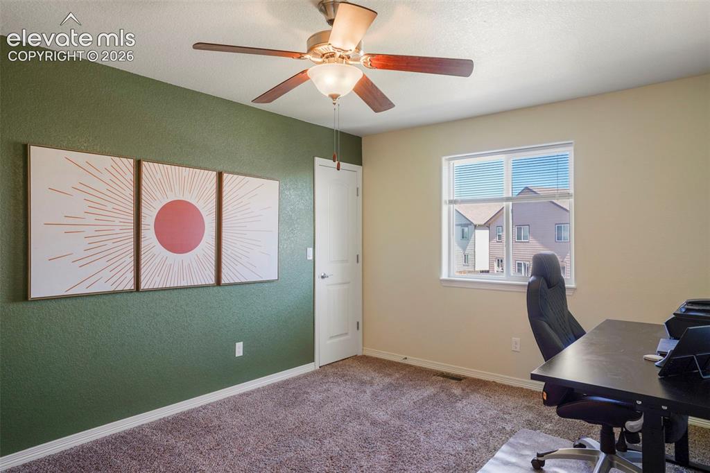 Image 20 of 32: Window with blinds, ceiling fan with light fixture, textured accent wall, p