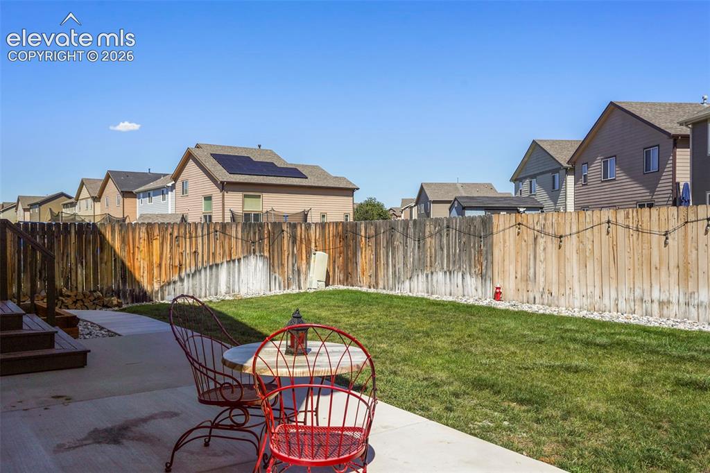Image 30 of 32: Expansive grassy lawn with a concrete patio, wood privacy fencing, and wood