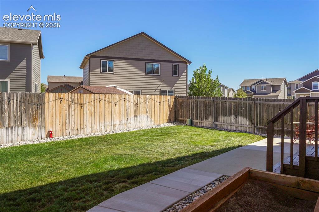 Image 31 of 32: Expansive backyard featuring a manicured lawn, concrete patio, privacy fenc