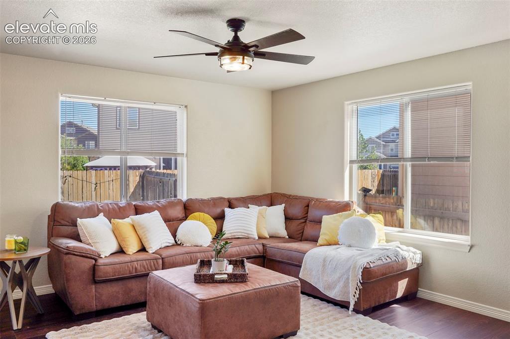 Image 6 of 32: Bright living area featuring wood-finish flooring, two large windows with b