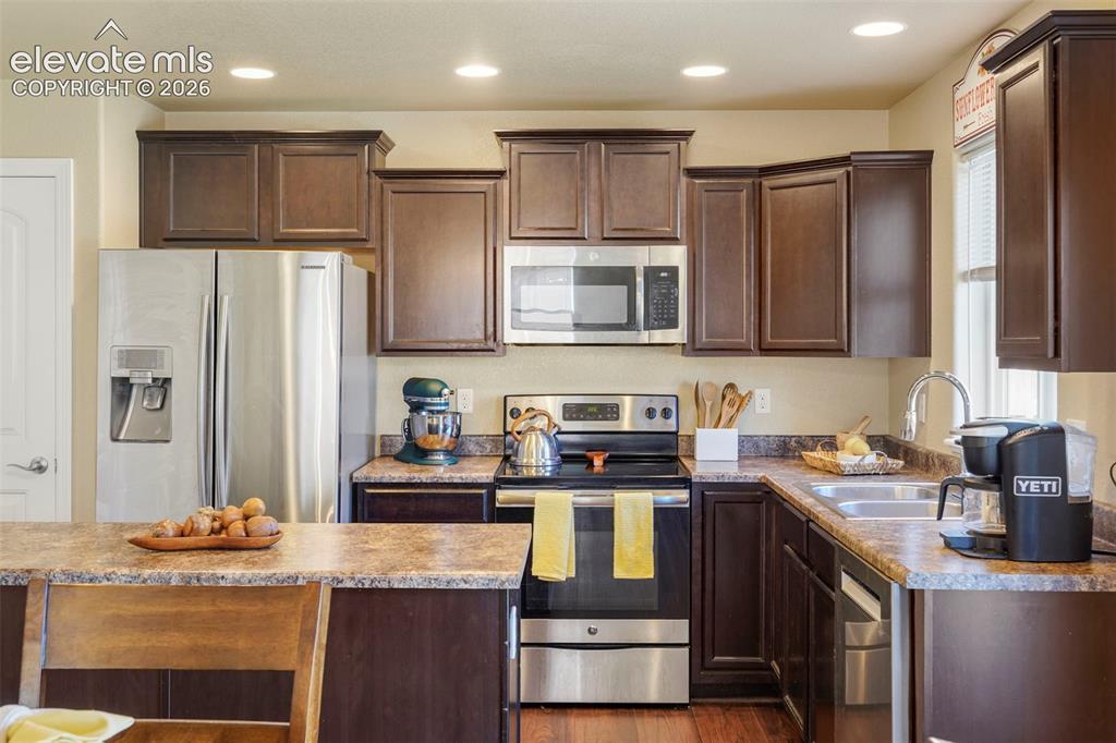 Image 9 of 32: Kitchen featuring dark wood-finish cabinetry, stainless steel appliances, r
