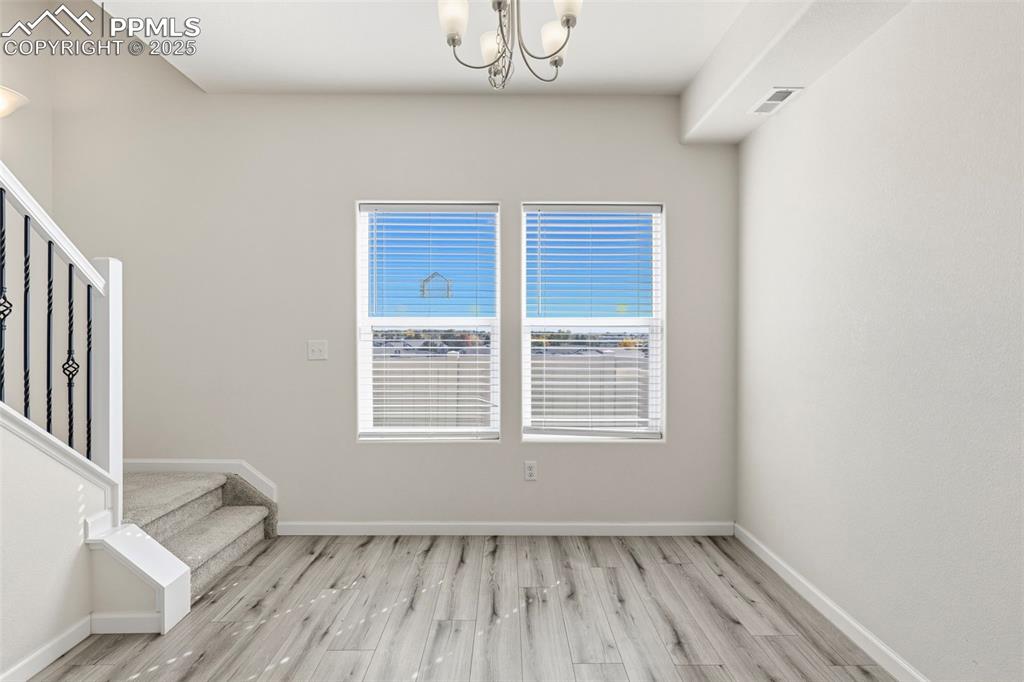 Image 15 of 35: Unfurnished dining area with light wood-style floors, a chandelier, and sta