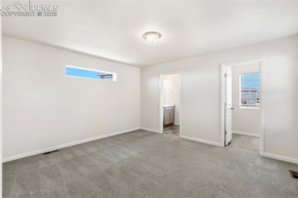 Image 22 of 35: Unfurnished bedroom with light carpet, a spacious closet, and ensuite bath