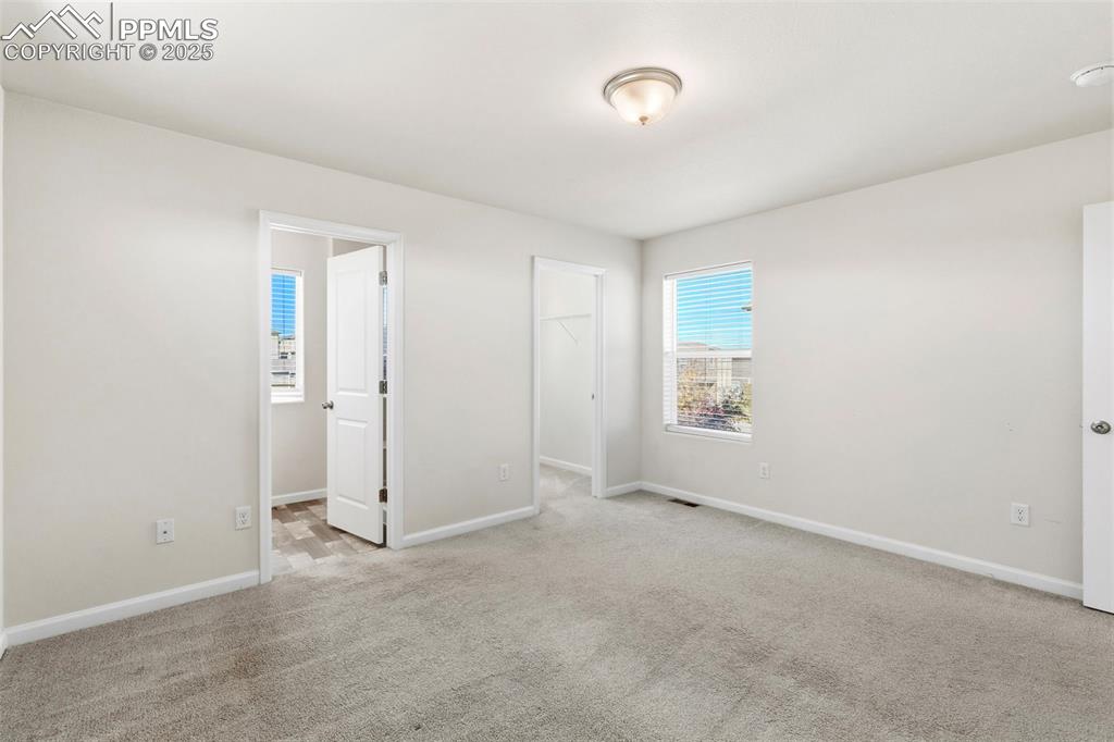 Image 23 of 35: Unfurnished bedroom with a walk in closet and light carpet