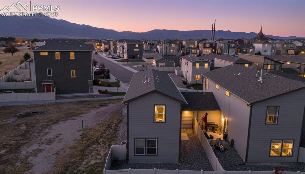 Image 3 of 35: Back of property at dusk with a fenced backyard, a residential view, and a